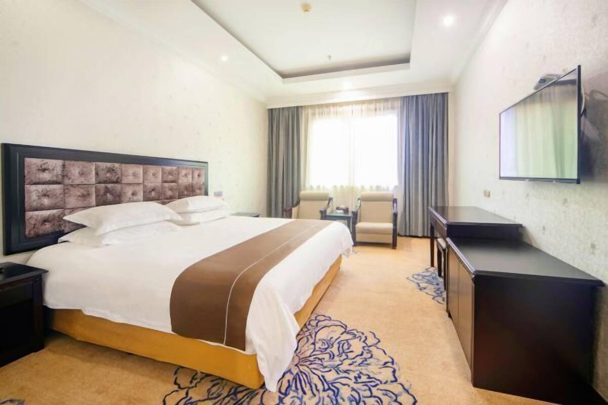 Una habitación de hotel con cama, escritorio, silla y televisión.