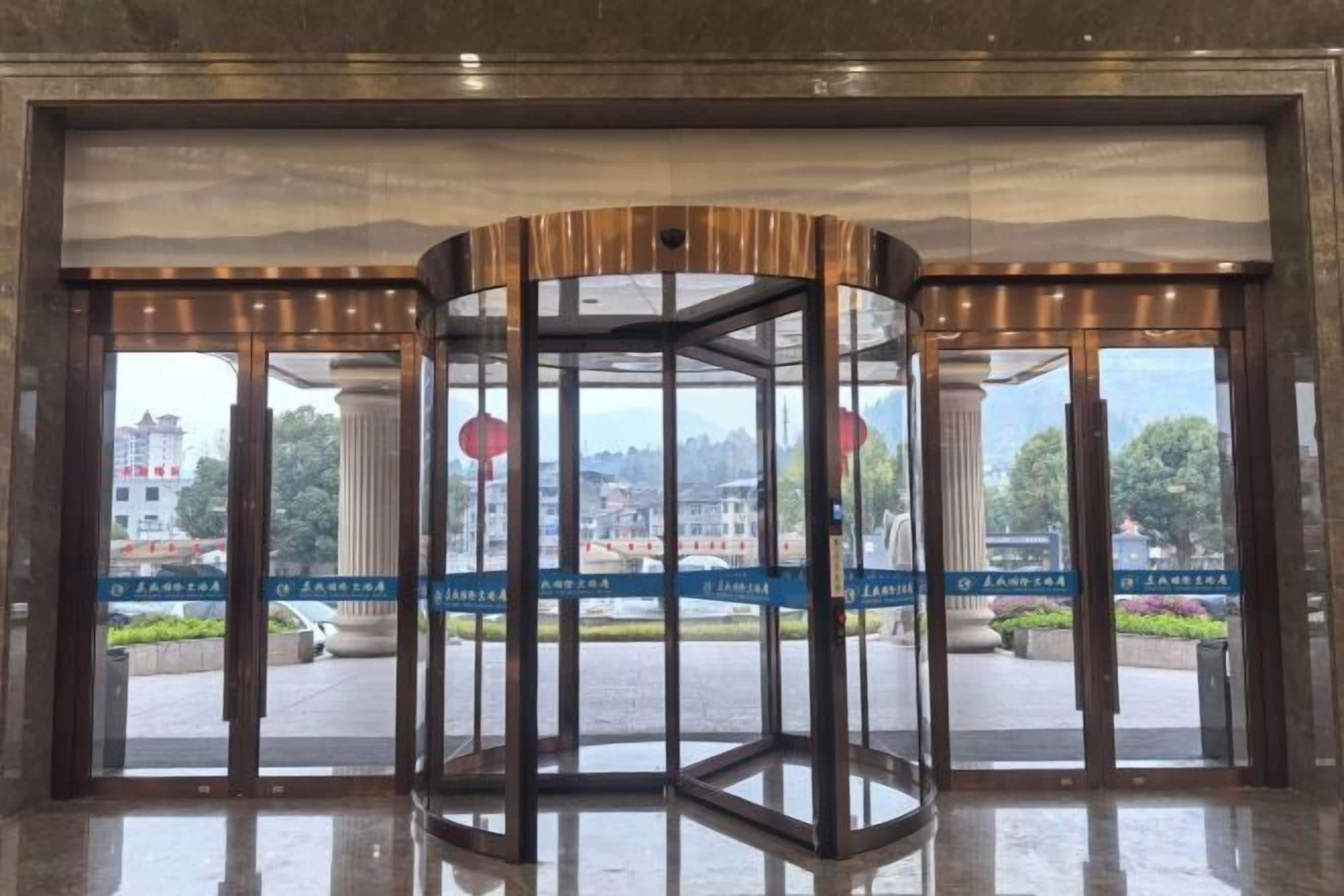 Una puerta giratoria con paneles de vidrio y vistas de un paisaje urbano.