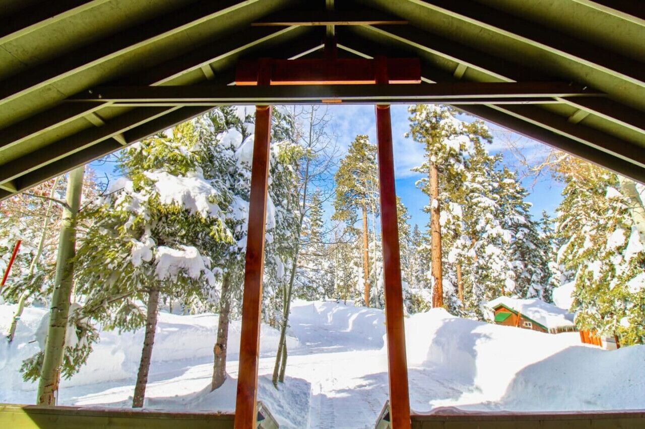 Bosque nevado con una estructura de madera al frente.