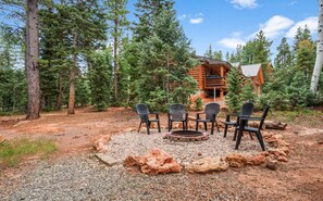 A cabin with a fire pit and four chairs in a forested area. - Lovely Log Cabin with Views and Fire Pit! (Duck Creek Village)