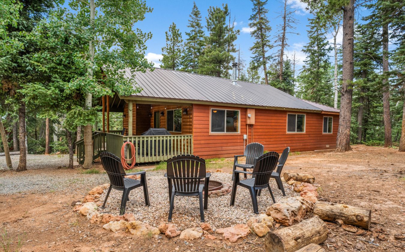 A cabin with a porch, outdoor seating, and a fire pit.