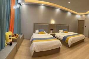 Quarto de hotel com duas camas, um sofá e uma janela grande.