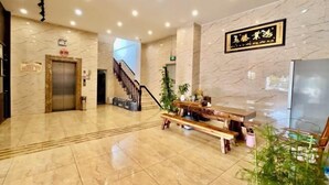 A hotel lobby with marble flooring, a reception desk, a staircase, and a sign with Chinese characters.