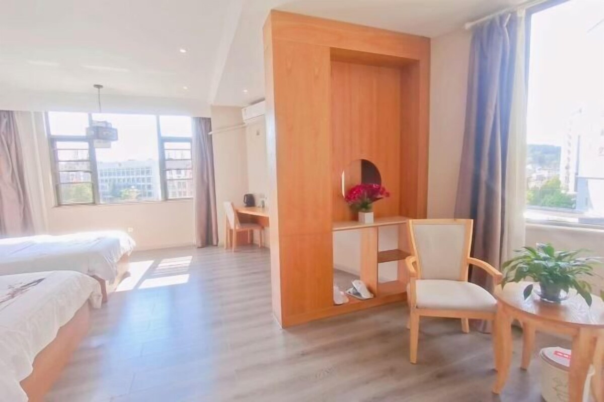 Ein Hotelzimmer mit zwei Betten, einem Schreibtisch, einem Stuhl und einem kleinen Tisch mit einer Pflanze.