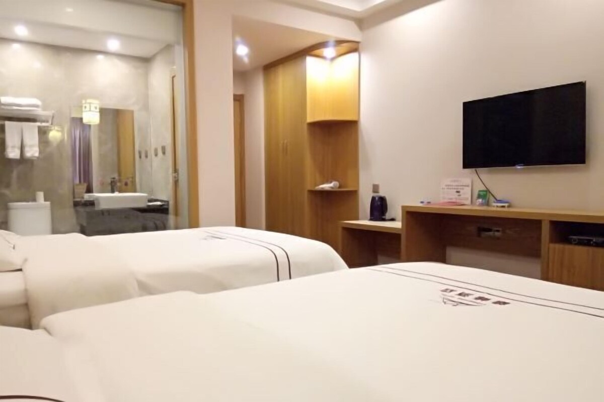 Ein Hotelzimmer mit zwei Betten, einem Fernseher, einem Holzschrank und einem Spiegel.