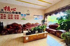 A lobby with leather sofas, a wooden coffee table, and potted plants. - Xiongfeng Hotel (Nanhua)