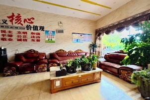 A lobby with leather sofas, a wooden coffee table, and potted plants.