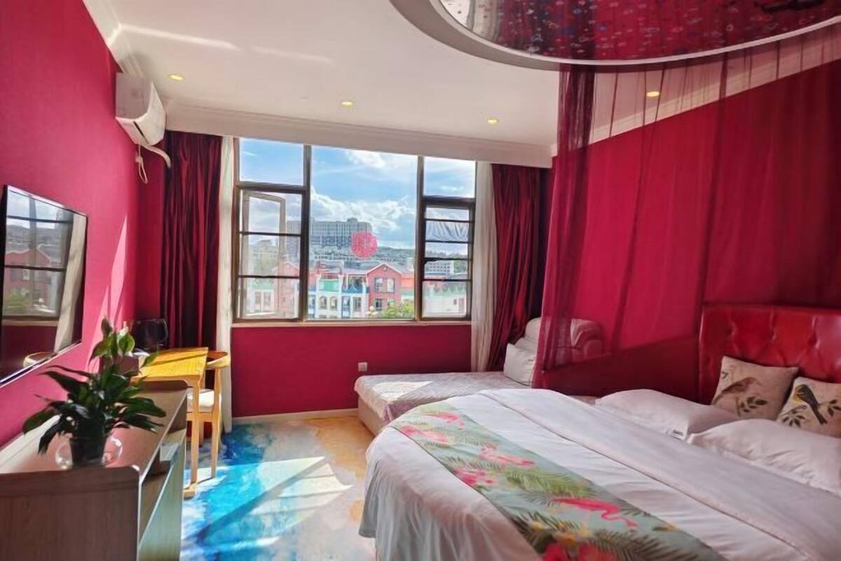 A room with a bed, a desk, and a window with a city view.