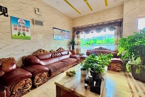 A lobby with a sofa set, a marble coffee table, and potted plants. - Xiongfeng Hotel (Nanhua)