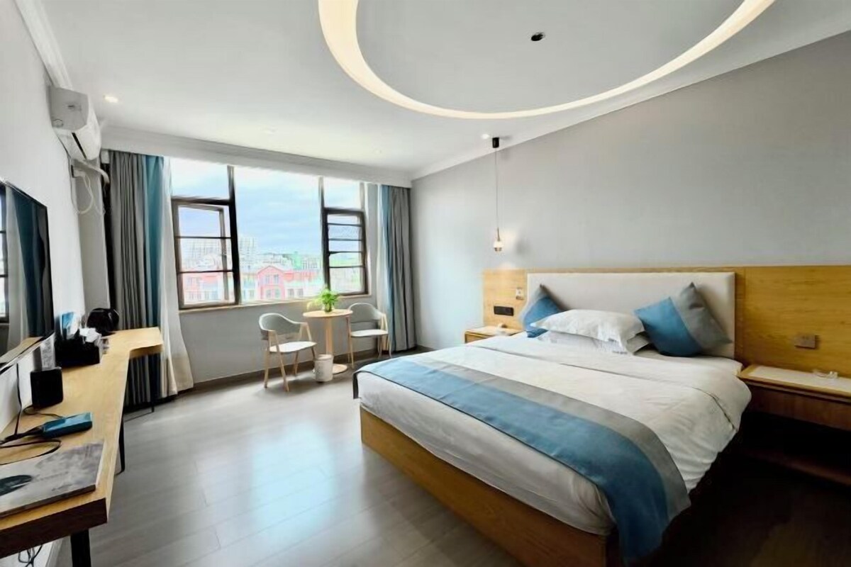 Ein Hotelzimmer mit Bett, Schreibtisch, Stuhl und Blick auf die Stadt.