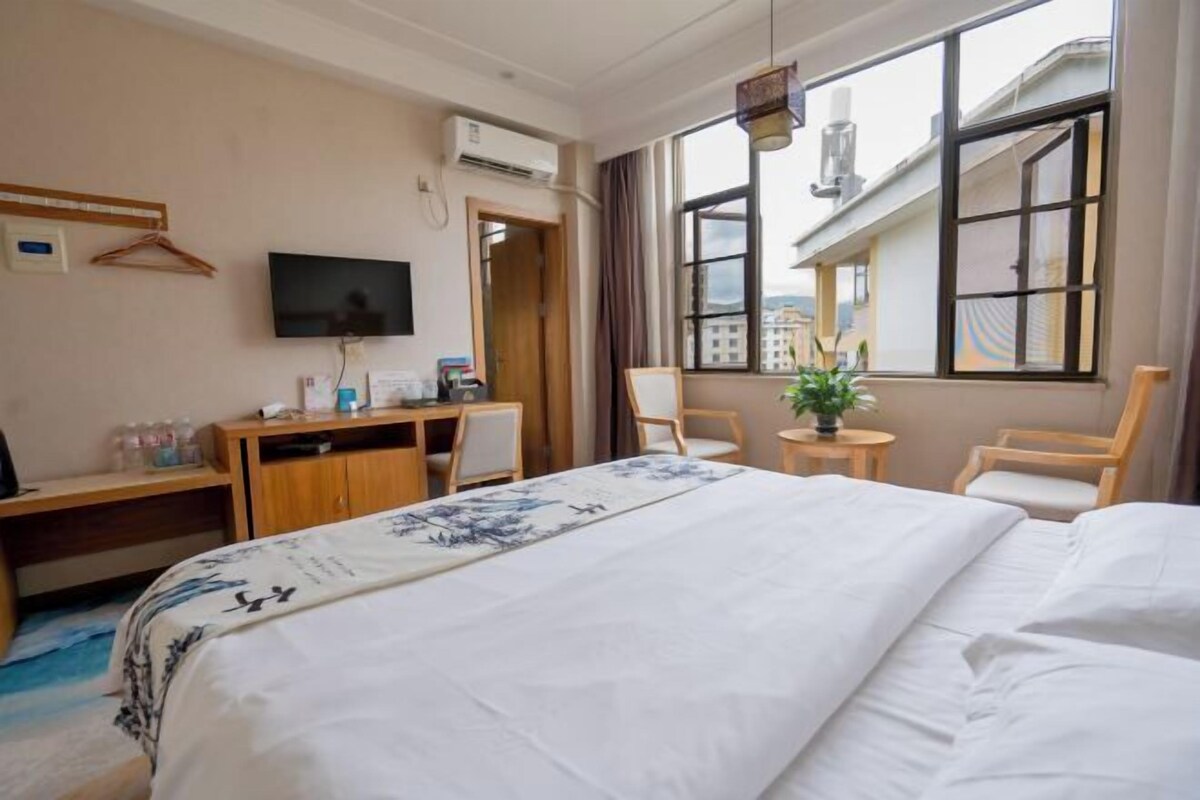 Ein Hotelzimmer mit Bett, Schreibtisch, Stuhl, Fernseher und einem Fenster mit Blick.