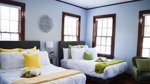 Une chambre d’hôtel avec deux lits, un fauteuil vert, une horloge murale et un élément décoratif mural.
