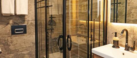 Un baño moderno con ducha cubierta por vidrio, inodoro blanco y tocador de madera con espejo.