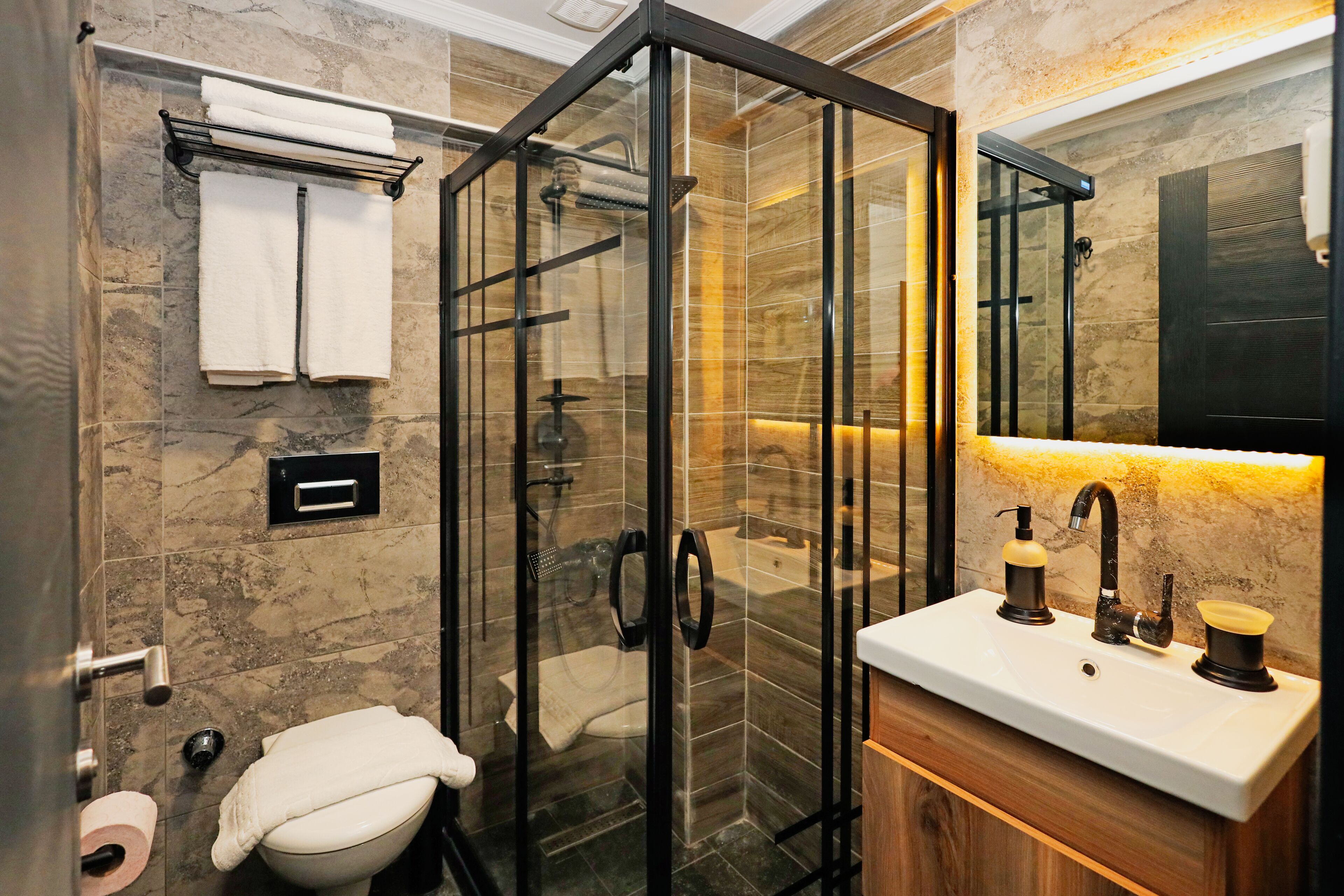 A modern bathroom with a glass-enclosed shower, a toilet, and a sink with a mirror above it.