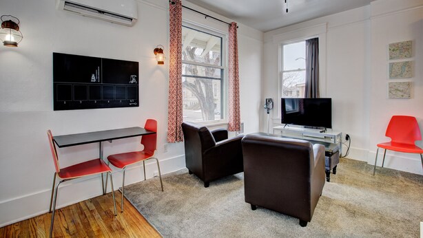 Un salon moderne doté d’un téléviseur à écran plat, de deux canapés en cuir, d’une table à manger avec des chaises et d’un ventilateur de plafond.