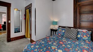 Une chambre à coucher avec un lit, une table de chevet, une lampe, un miroir et une porte.