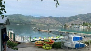 Un muelle a orillas del lago con barcos, un pequeño edificio y una mesa de picnic.