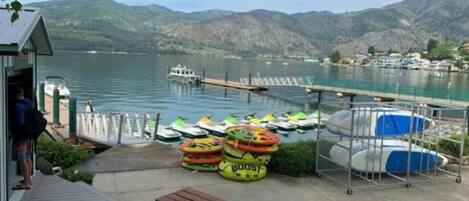 Un muelle a orillas del lago con barcos, un pequeño edificio y una mesa de picnic.