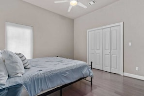 Un dormitorio con cama, ventilador de techo y puerta.