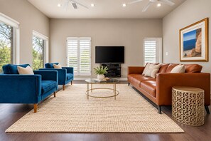 A modern living room with a flat-screen TV, two sofas, a coffee table, and a patterned rug.