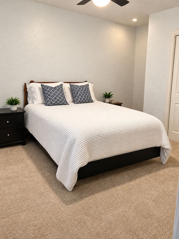 A bedroom with a bed, nightstands, a ceiling fan, and a door. - McKenzie Cove - Private dock & lake views (Hot Springs)