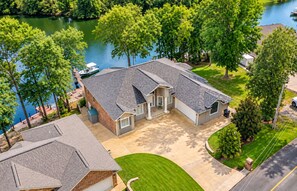 A two-story house with a garage, a covered driveway, and a boat docked by the water.