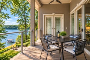 A covered outdoor patio with a table and chairs, overlooking a lake.