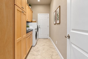 A narrow hallway with wooden cabinets, a washing machine, and a white door. - McKenzie Cove - Private dock & lake views (Hot Springs)