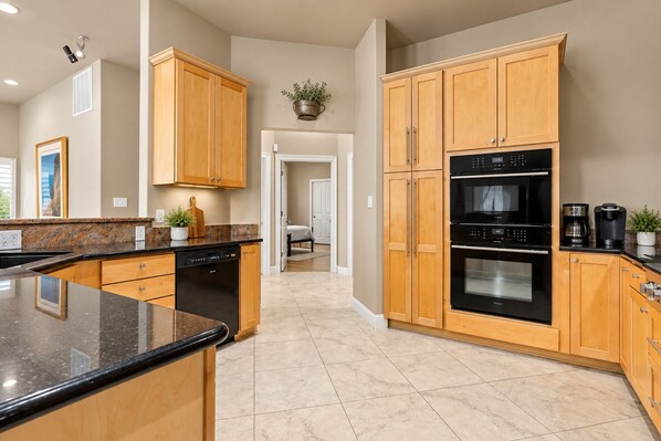 A modern kitchen with wooden cabinets, a dishwasher, an oven, and a coffee maker.