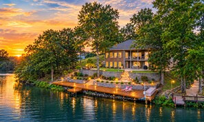 A waterfront property with a dock, outdoor seating, and a large house with multiple windows. - McKenzie Cove - Private dock & lake views (Hot Springs)