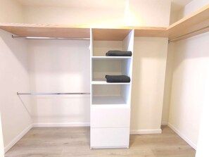 A walk-in closet with a wooden shelf, a hanging rod, and a sliding door.