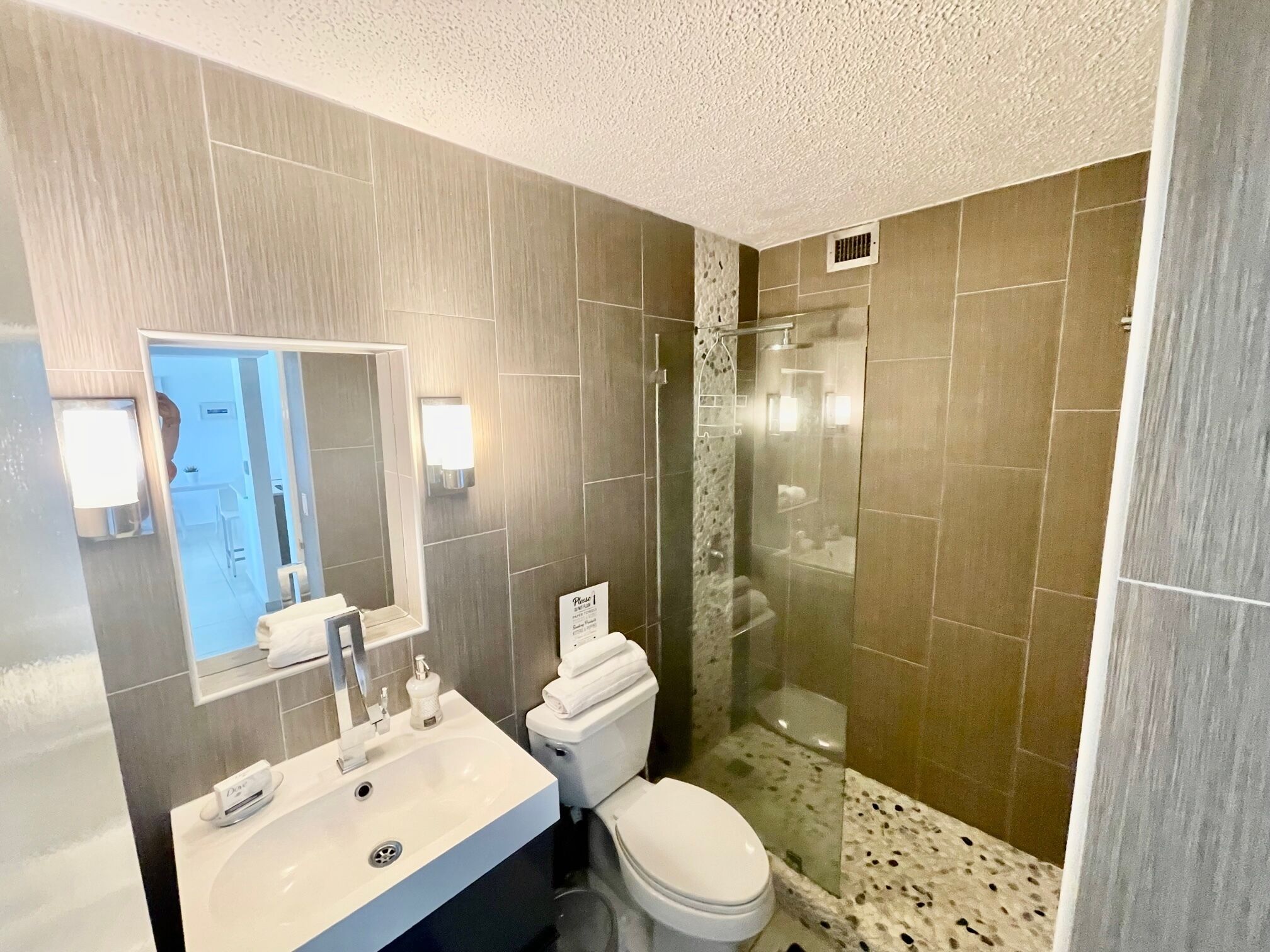 A modern bathroom with a sink, toilet, and glass-enclosed shower.
