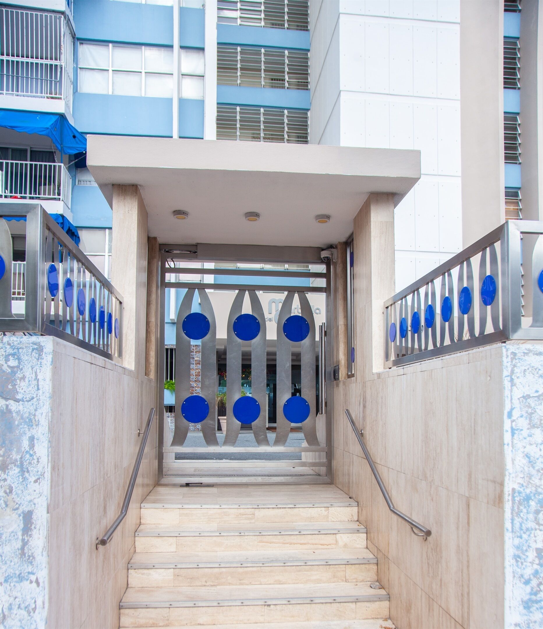 A staircase leading to a building entrance with a metal railing and blue circular decorations.