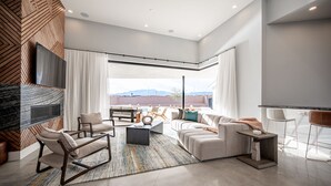 A modern living room with a large window, a fireplace, and a view of the mountains.