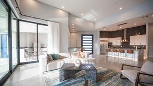 A spacious living area with a modern sofa, a coffee table, and a view of the kitchen.