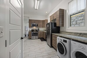A modern kitchen with stainless steel appliances, wooden cabinets, and a built-in washer and dryer. - Boise-Downtown-historical-unique Arthouse 2 (Boise)