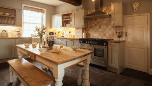 A kitchen with a wooden table, bench, and a stove. - Manor House (York)