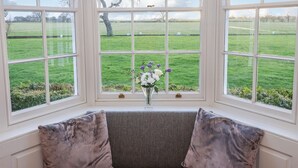 A room with a large bay window overlooking a green field. - Manor House (York)
