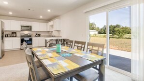 A modern kitchen with white cabinets, a microwave, and a dining area with a table set for four.
