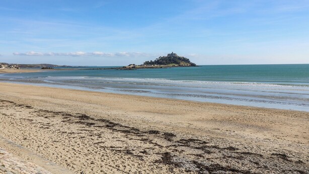 A beach with a distant island and calm sea. - Tregonning Lodge (Helston)