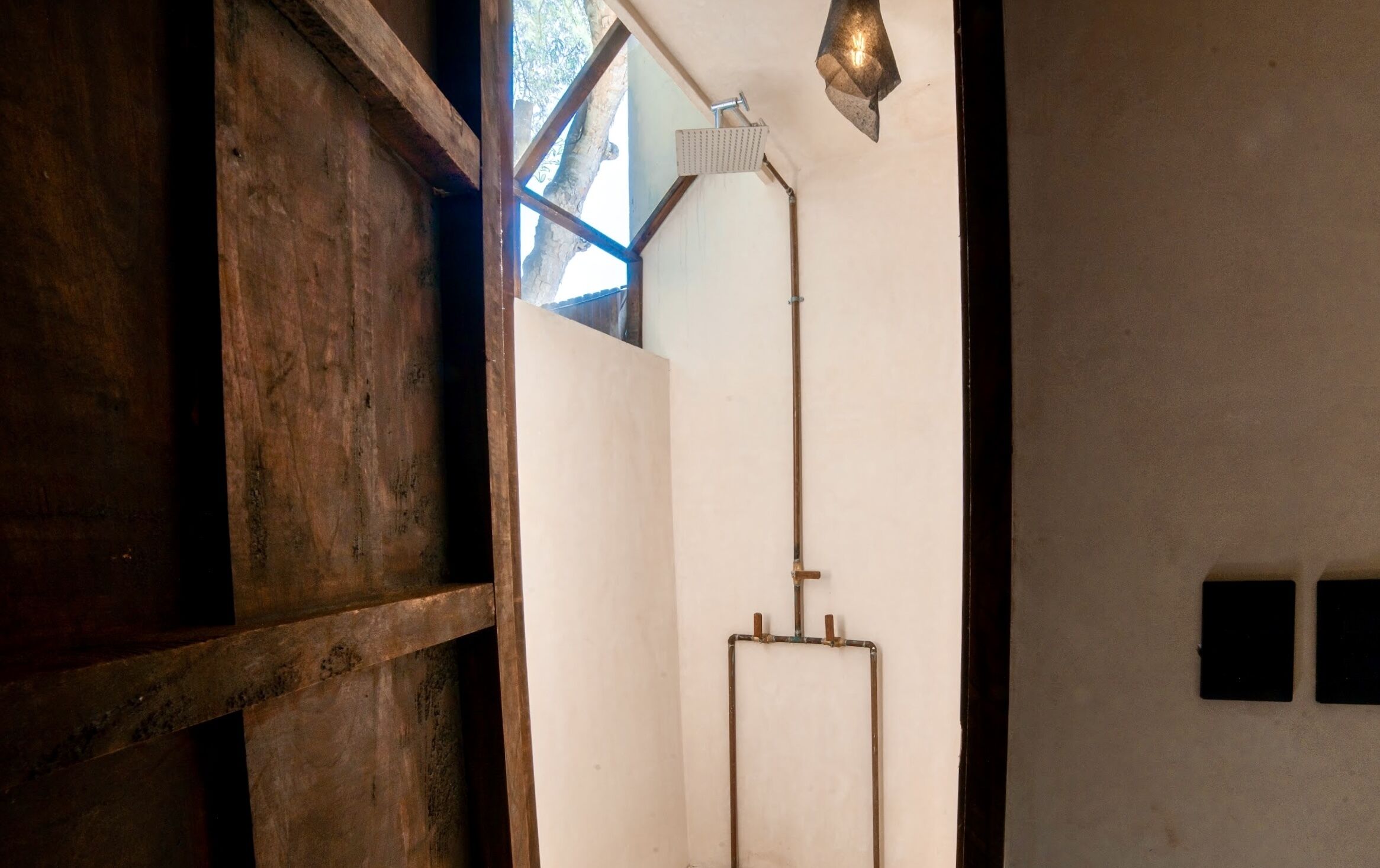 A bathroom with a shower, wooden beams, and a window.