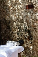 A stone wall with a towel and a black object on a table.