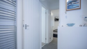 Un couloir avec un radiateur en métal, des portes blanches et un tableau encadré accroché au mur.