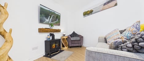 A living room with a fireplace, a sofa, a chair, and a large wooden sculpture.