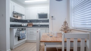 Une cuisine moderne avec des meubles blancs, une table à manger en bois et un arbre décoratif.