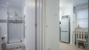 Une salle de bain moderne avec une douche à l’italienne en verre, des toilettes blanches et un tapis bleu.