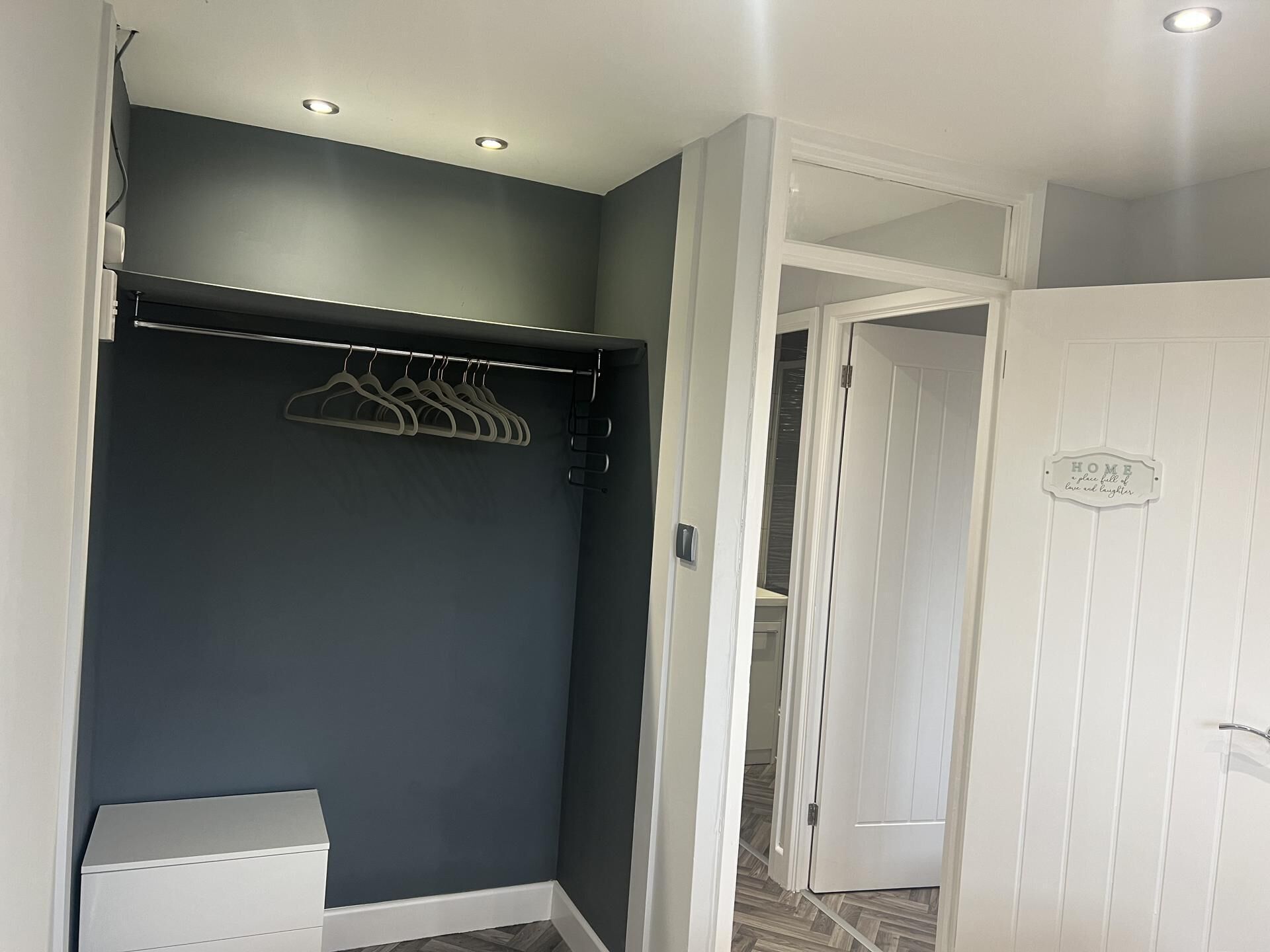 Un dressing avec un mur de couleur sombre, une porte blanche et une tringle à vêtements.