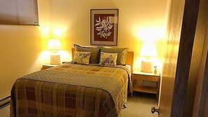Un dormitorio con una cama grande, dos mesitas de noche y dos lámparas.