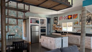 A modern kitchen with a refrigerator, oven, and dining area.