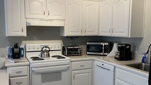 A kitchen with white cabinets, a stove, a microwave, and a dishwasher. - Bright Condo With Views & Easy Access to CDA River.  Minutes From Gondola! (Kellogg)